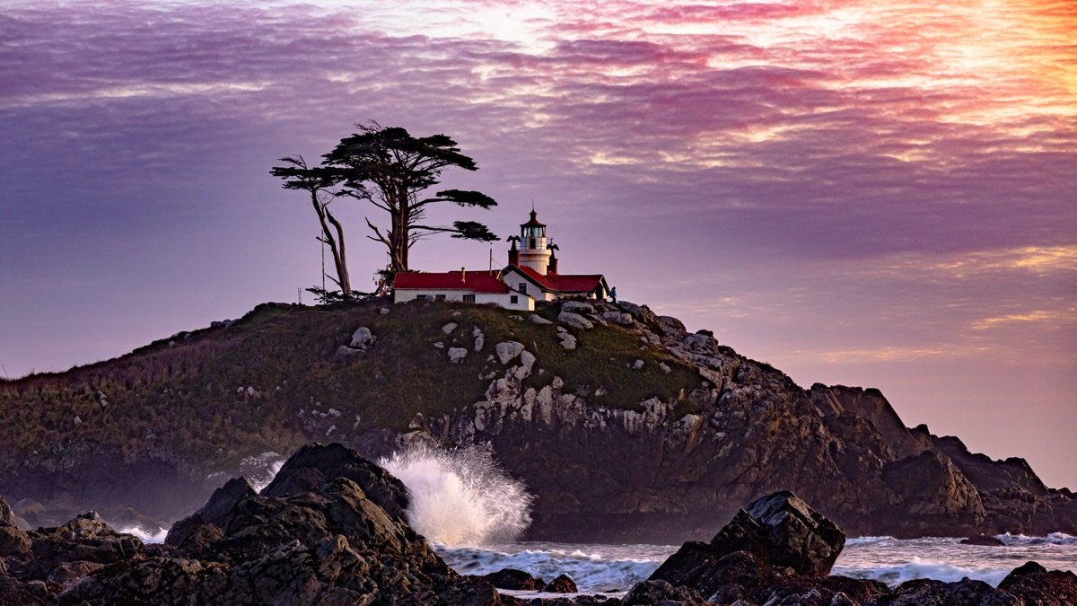 A lighthouse on its headland beneath windswept cypress at sunset — "Crescent City Lighthouse", a fine art print by Matthew Archer